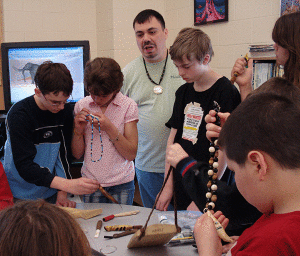 Donald Gregory (Heindei), a Tlingit artist from Alaska, shows students examples of his crafts and explains the meaning behind the representations.