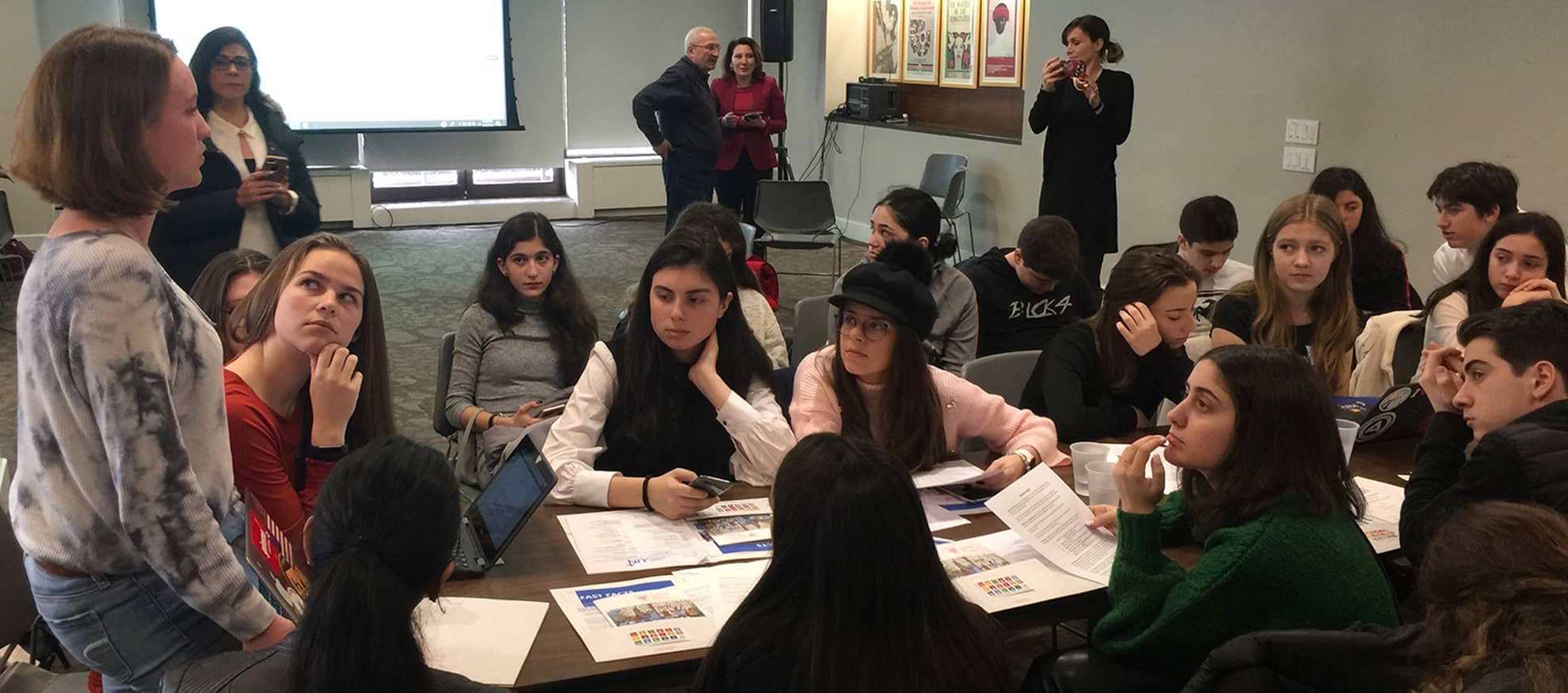 Lilian Oxley (standing) helps guide discussion among students from Mexico, the Republic of Georgia, New York and New Jersey on the subtheme: Science-based facts and predictions related to climate change. In the background are teachers from these schools, who are there to observe but not intervene.