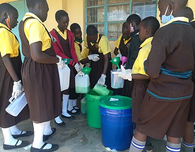 Students decanting liquid soap into 5-liter jugs that are sold to shops and schools, providing a sustainable revenue stream.